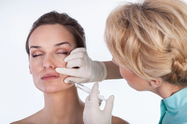 Woman receiving a cosmetic injectable treatment near her lips, highlighting the importance of precise placement for balanced facial aesthetics.